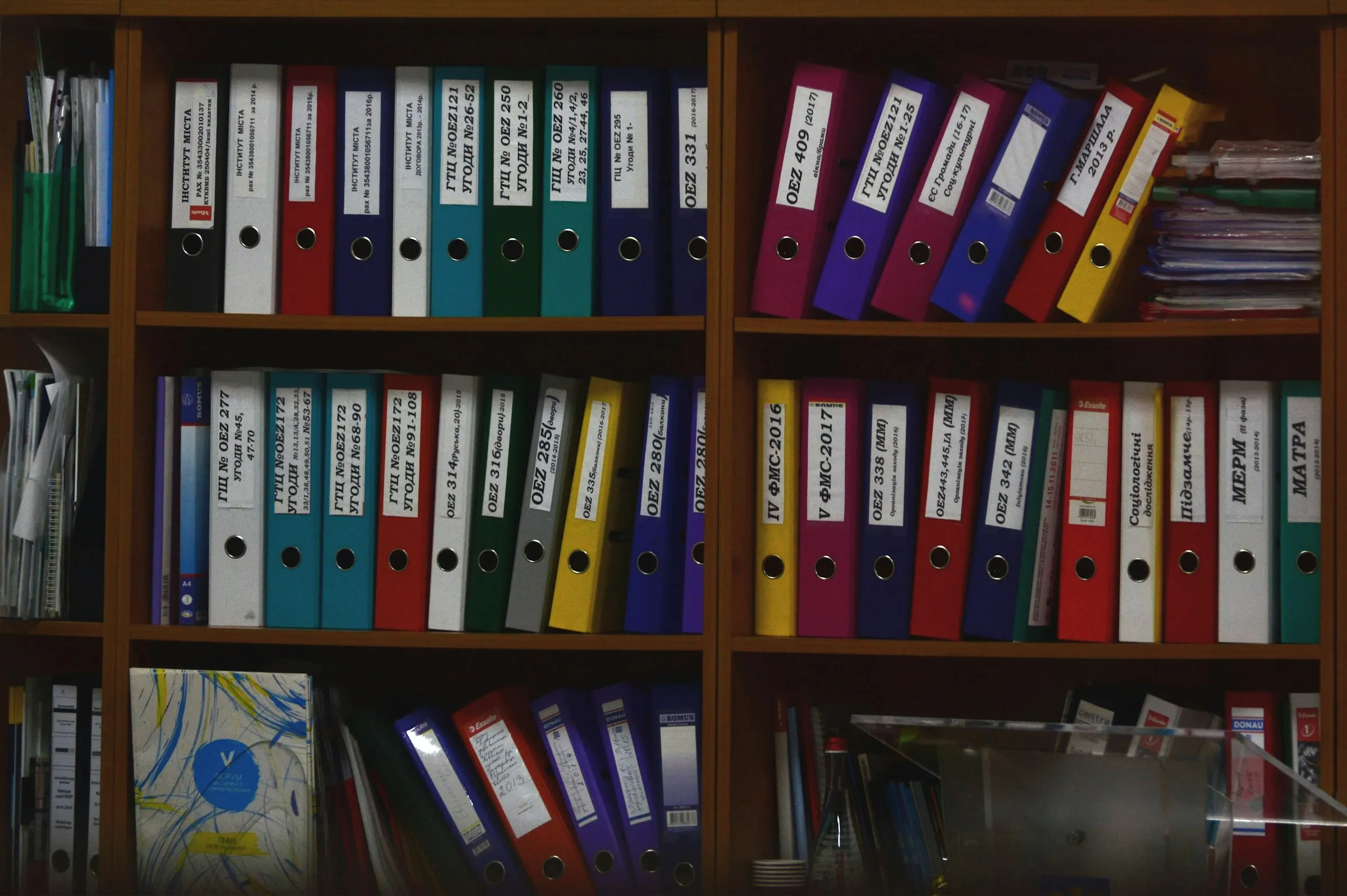 A shelf displaying an array of colorful binders in various shades, organized neatly for easy access.