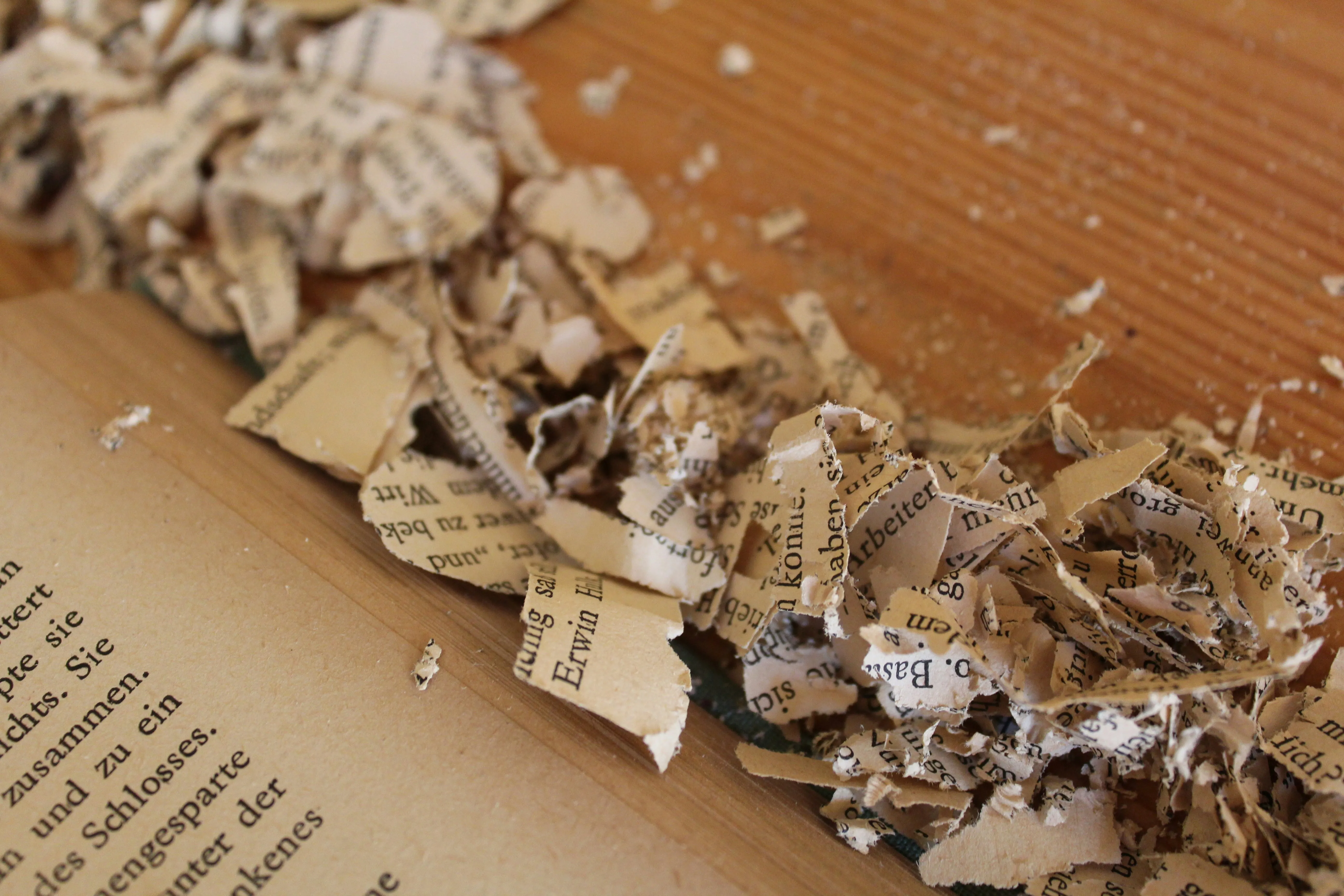 A collection of old newspaper sheets piled on a wooden table, displaying vintage articles and worn edges.